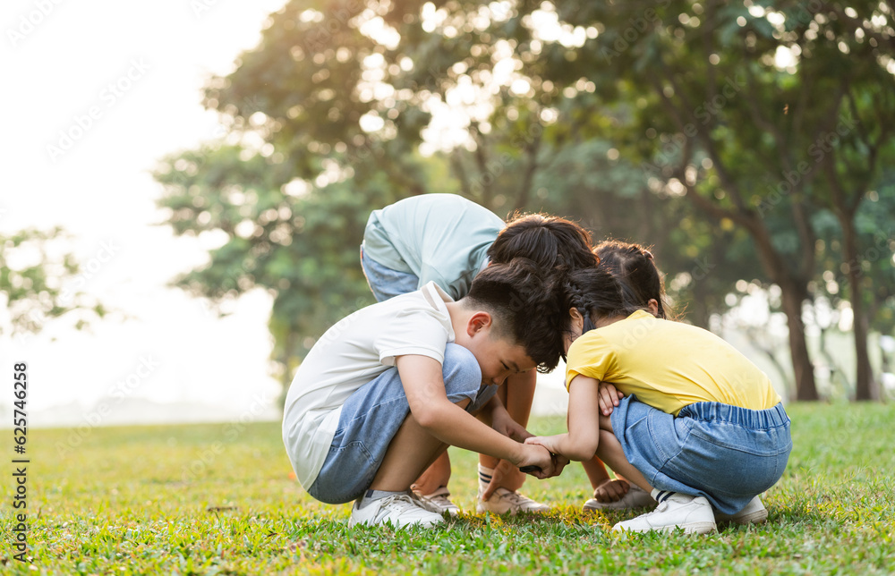 image of asian kids using magnifying glass in park image of asian kids using magnifying glass in park