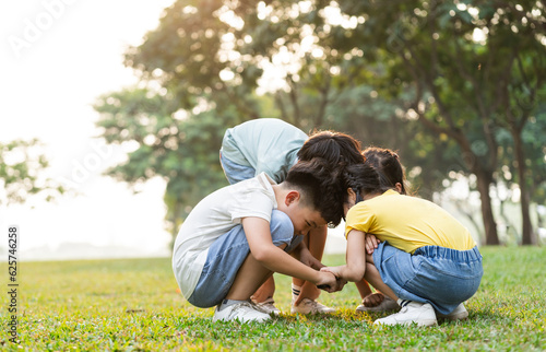 image of asian kids using magnifying glass in park