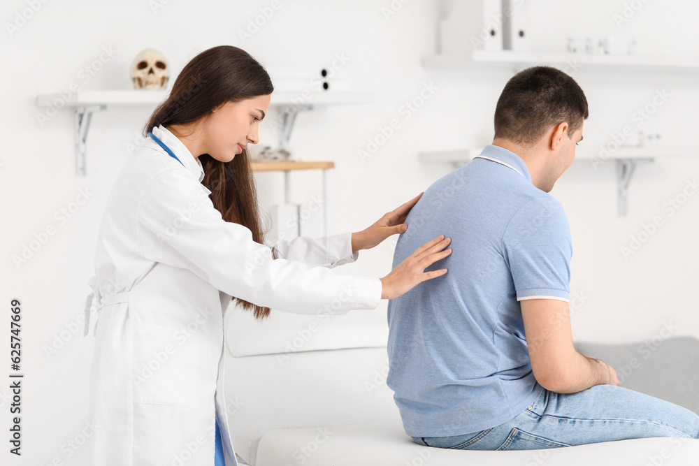 Obraz premium Female doctor checking posture of young man in clinic