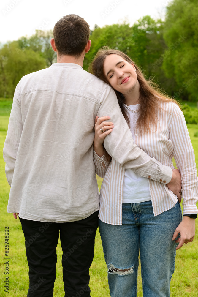 Beautiful happy loving couple hugging and walking in park on spring day Beautiful happy loving couple hugging and walking in park on spring day