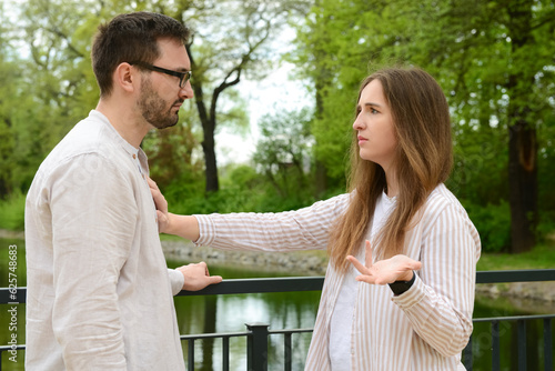 Beautiful couple arguing on bridge in park photo