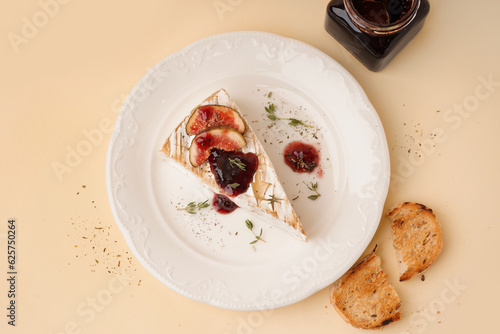 Plate with tasty baked Camembert cheese on yellow background