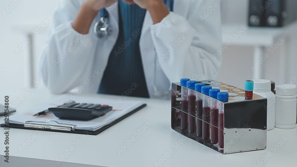 Medical worker in lab coat and sterile mask, doing a microscope analysis while her colleague are working behind Medical worker in lab coat and sterile mask, doing a microscope analysis while her colleague are working behind