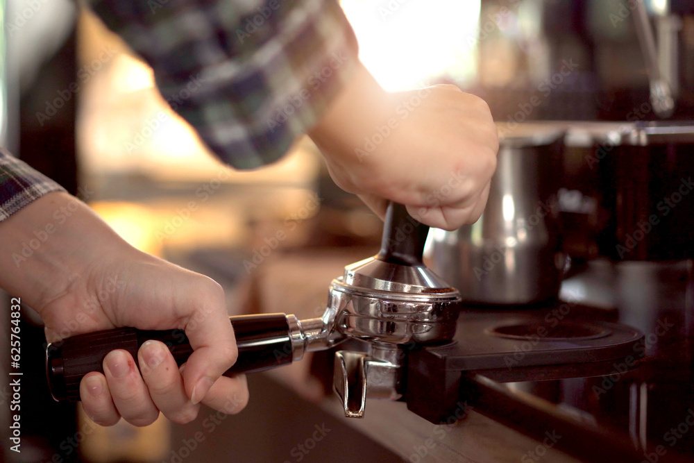 barista making an espresso coffee from the professional espresso machine in coffee shop. Espresso maker machine with portafilter close up.