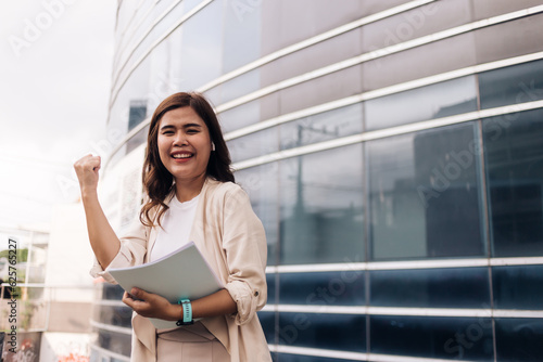 Free Download Successful businesswoman standing in front of office building and holding document. - GFXLoad