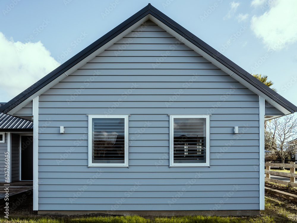 Gray suburban house with overlapping wood siding and gabled metal roof. Front view. Gray suburban house with overlapping wood siding and gabled metal roof. Front view.