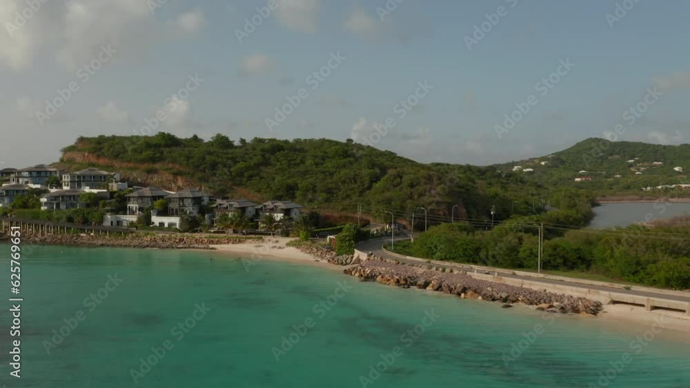 Aerial view scenic Antigua and Bermuda crystal clear turquoise coastline with coastal asphalt road and luxury real estate property buildings in sunny day in Caribbeans Aerial view scenic Antigua and Bermuda crystal clear turquoise coastline with coastal asphalt road and luxury real estate property buildings in sunny day in Caribbeans