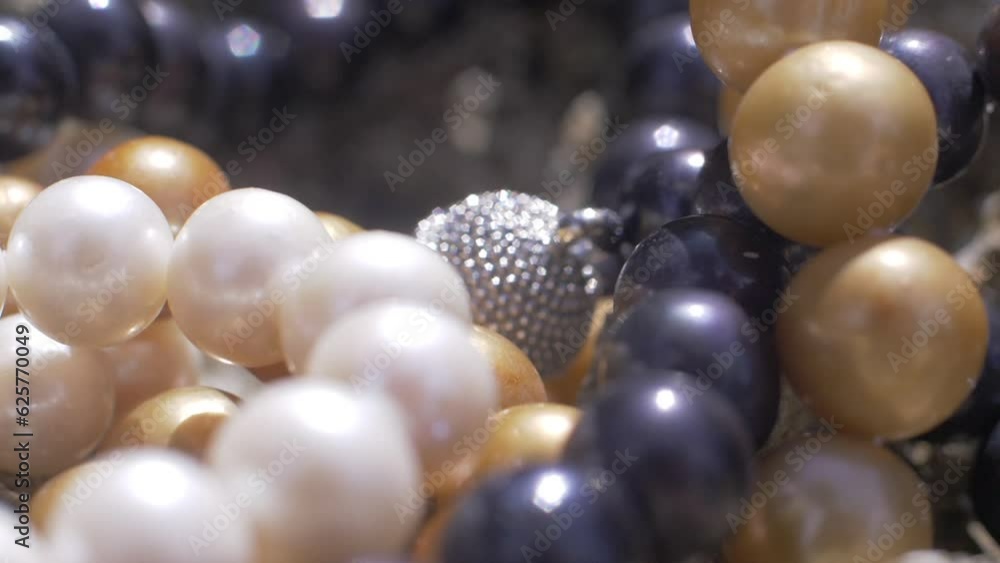 Close up cinematic shot of various pearl necklaces in white, blue and yellow with silver jewellery on rock, 120 FPS, Slomo Close up cinematic shot of various pearl necklaces in white, blue and yellow with silver jewellery on rock, 120 FPS, Slomo