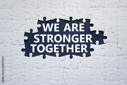 We are stronger together symbol. White puzzle with words We are stronger together. Beautiful black background. We are stronger together concept. Copy space.