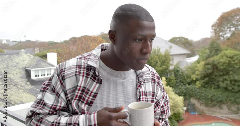 Portrait of happy african american man standing on balcony and drinking coffee at home, slow motion Portrait of happy african american man standing on balcony and drinking coffee at home, slow motion