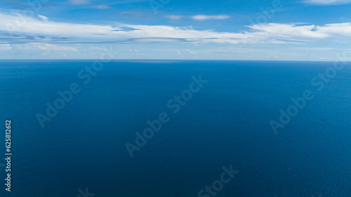 Blue sea water with waves against sky and clouds. Seascape in the tropics. Borneo, Malaysia.