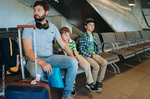 Father and children in airport with backpack and suitcase waiting for flight. Travelling with kids