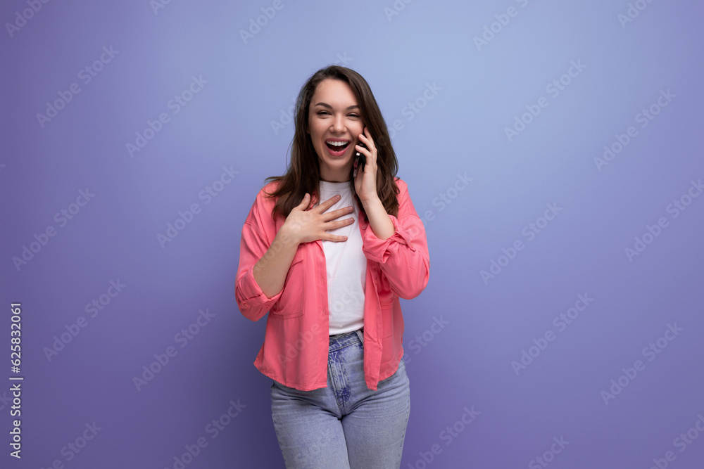 young woman in a pink shirt and jeans chatting on the phone on a studio isolated background young woman in a pink shirt and jeans chatting on the phone on a studio isolated background