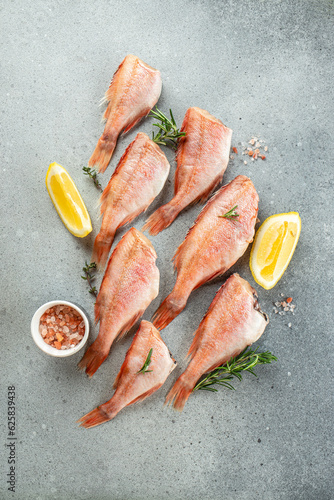 Raw fish perch with lemon, rosemary, salt on a light background. vertical image. top view. place for text