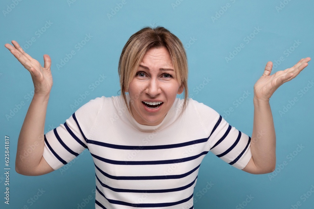 emotional angry blond girl in a striped sweater on a blue background with copy space emotional angry blond girl in a striped sweater on a blue background with copy space