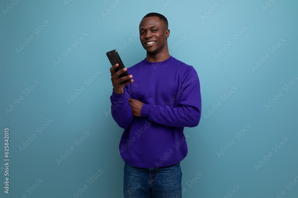 handsome young african guy in blue sweatshirt is using phone handsome young african guy in blue sweatshirt is using phone