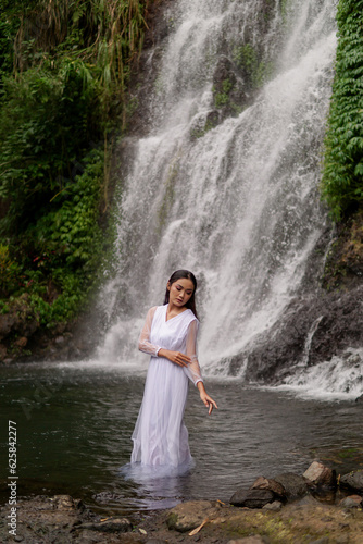 Fototapeta Naklejka Na Ścianę i Meble -  Young Girl in White Shirt poses near Jagir Waterfall in Banyuwangi