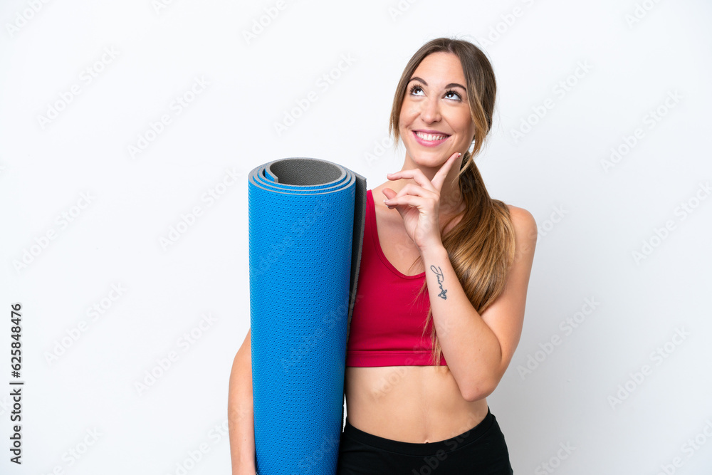 Young sport woman going to yoga classes while holding a mat isolated on white background thinking an idea while looking up Young sport woman going to yoga classes while holding a mat isolated on white background thinking an idea while looking up