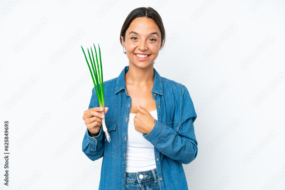 Young hispanic woman holding chive isolated on white background with surprise facial expression Young hispanic woman holding chive isolated on white background with surprise facial expression