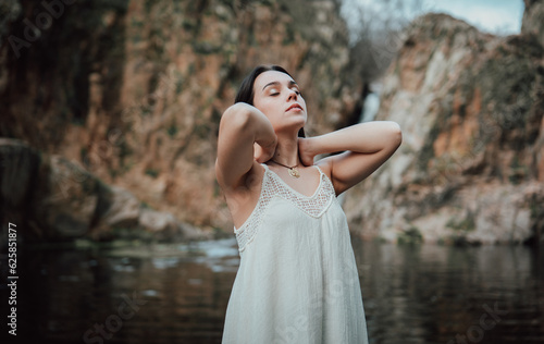 Joven modelo con vestido blanco posa dentro de un lago