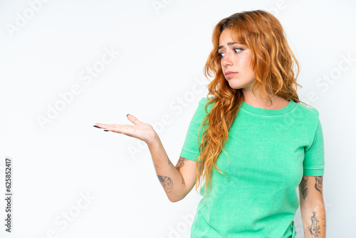 Young caucasian woman isolated on white background holding copyspace with doubts