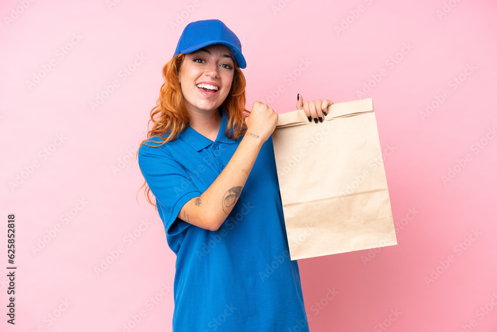 Young caucasian woman taking a bag of takeaway food isolated on pink background celebrating a victory Young caucasian woman taking a bag of takeaway food isolated on pink background celebrating a victory