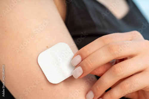 woman sticks a medical microneedle plaster photo
