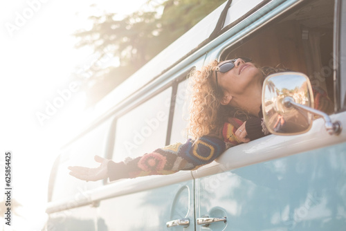 Travel and happiness. Freedom feeling enjoying life concept lifestyle people. One woman traveling as a passenger inside classic vintage van and have fun opening arms outside the windows. Vacation