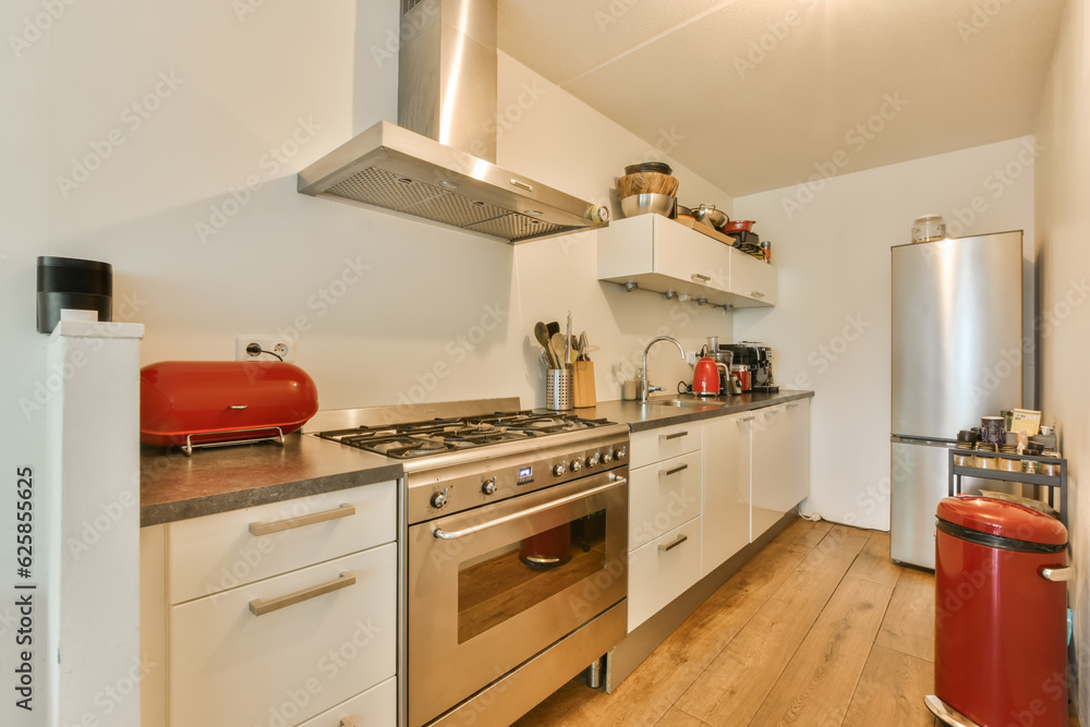 Fototapeta premium a kitchen with wood flooring and white cupboards on the wall behind it is a stove, dishwasher and refrigerator