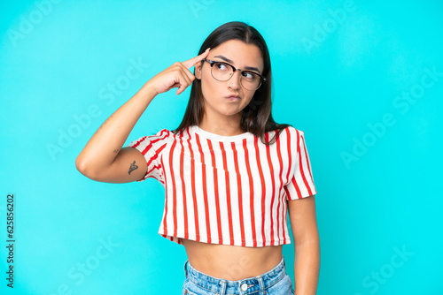 Young caucasian woman isolated on blue background making the gesture of madness putting finger on the head