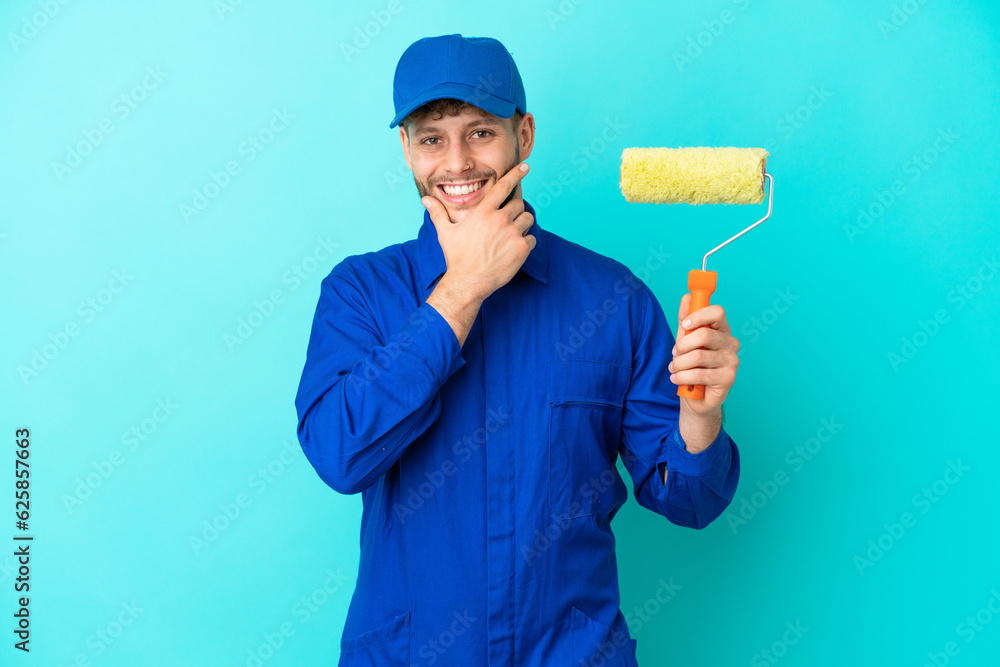 Painter caucasian man isolated on blue background happy and smiling Painter caucasian man isolated on blue background happy and smiling