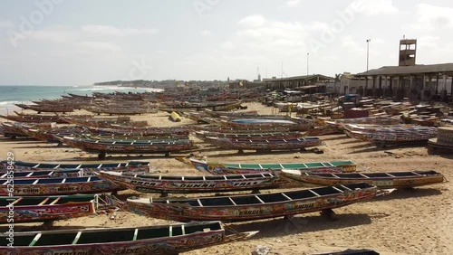 The camera glides over sprawling formation of colorful wooden fishing boats before ascending to reveal a beautiful view of the Atlantic. Filmed in the fishing village of Kayar (Senegal, West Africa).