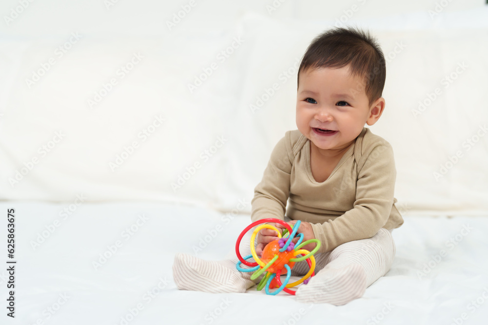 infant baby playing with colorful rubber bites toy on bed infant baby playing with colorful rubber bites toy on bed
