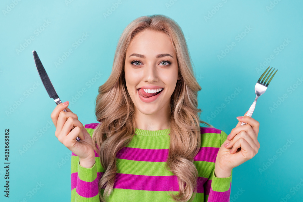Photo of satisfied woman with curly hairstyle dressed striped sweatshirt holding cutlery lick lips isolated on teal color background Photo of satisfied woman with curly hairstyle dressed striped sweatshirt holding cutlery lick lips isolated on teal color background
