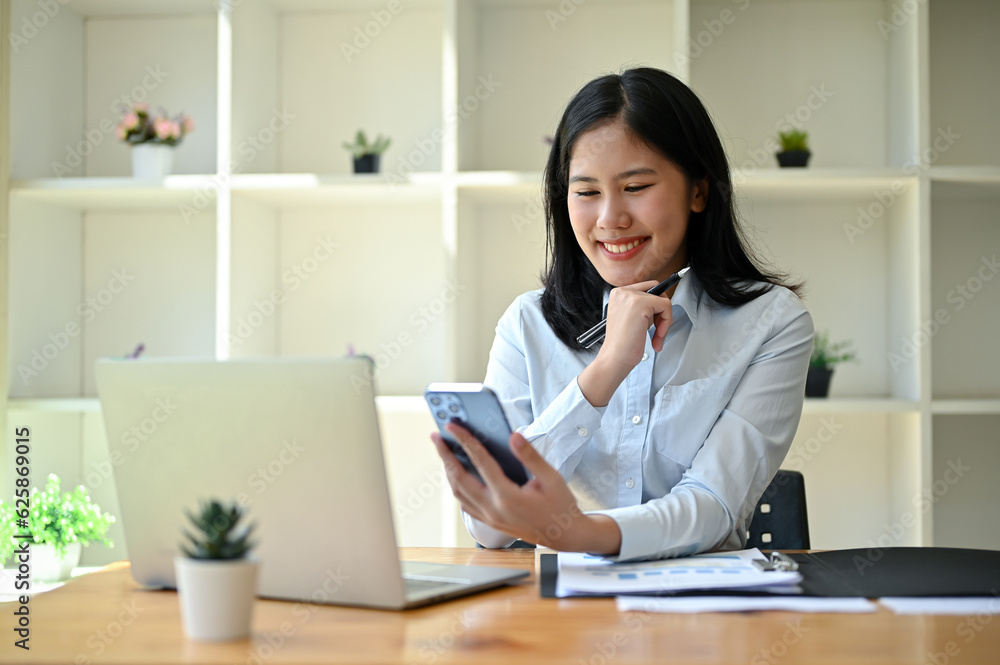 A beautiful Asian businesswoman is looking at her phone screen and reading messages A beautiful Asian businesswoman is looking at her phone screen and reading messages