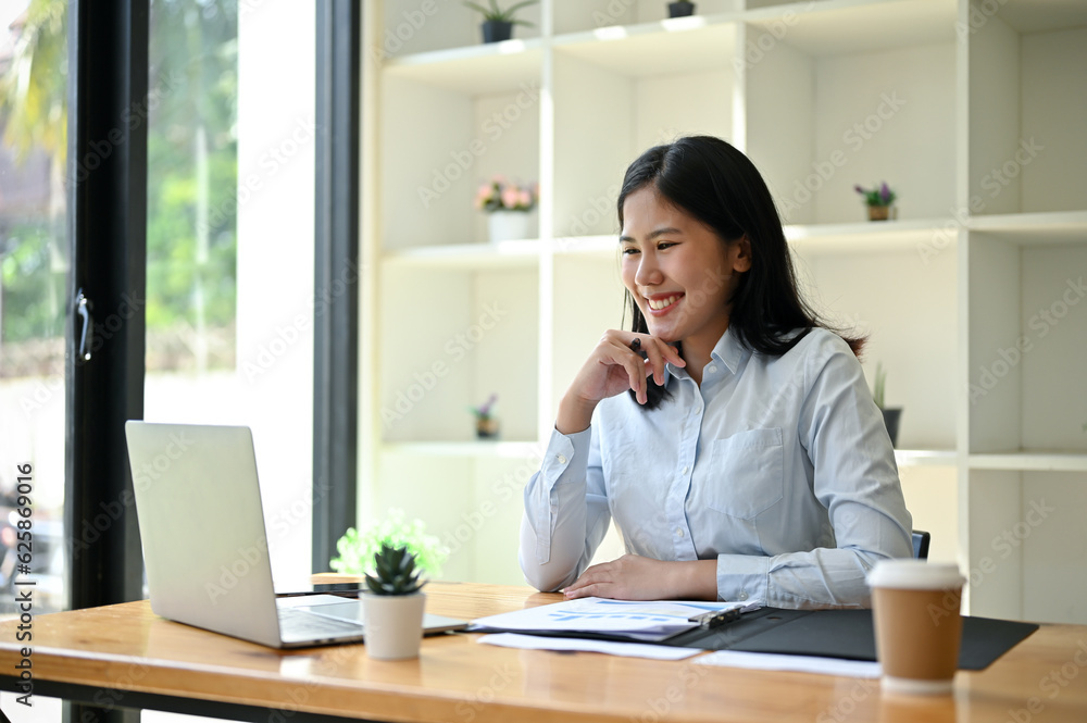A happy Asian businesswoman having an online meeting with her team while working at her desk A happy Asian businesswoman having an online meeting with her team while working at her desk