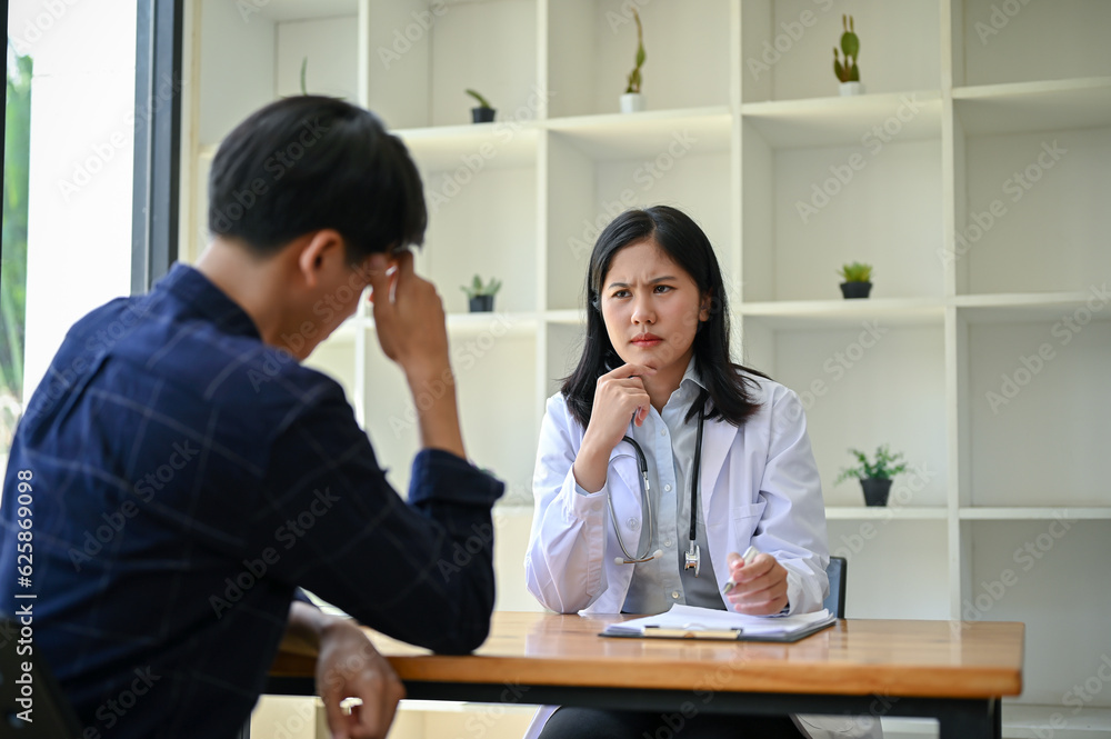 A stressed and serious Asian female doctor is having a serious meeting with a patient A stressed and serious Asian female doctor is having a serious meeting with a patient