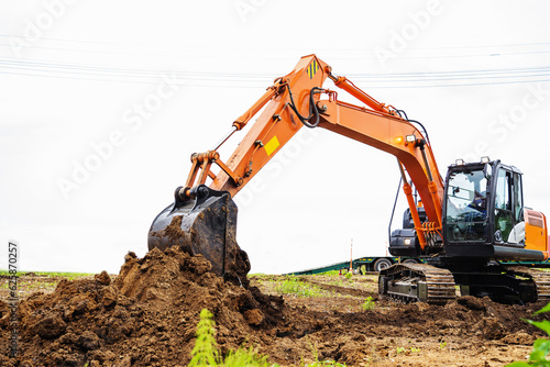 The excavator digs the ground. The work of heavy equipment on the laying of a pipeline or other industrial excavations. Side view.