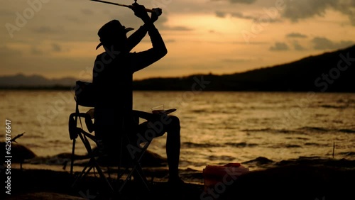 Silhouette of fishermen alone recreation with fishing rod outdoor catching lifestyle fish at sunset photo