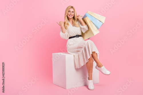 Full body cadre of wavy hair girl sit white box directing her finger mockup new gucci store bargains isolated over pink color background