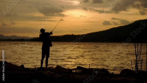 Silhouette of fishermen alone recreation with fishing rod outdoor catching lifestyle fish at sunset photo