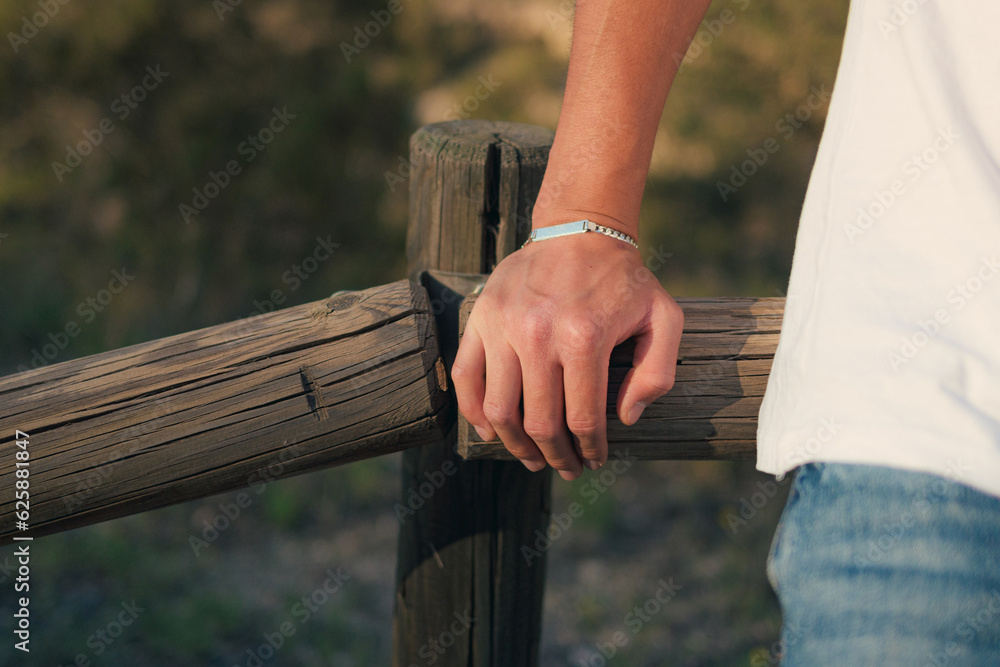Hand of a man with a silver bracelet at sunset - obrazy, fototapety, plakaty 