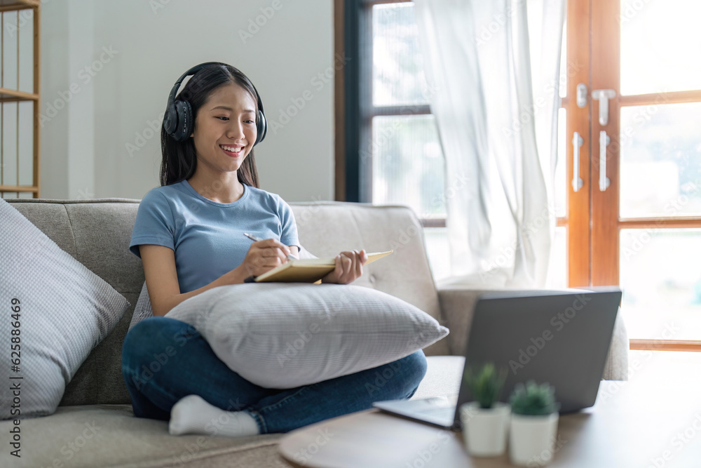 Female people using laptop computer at home smiling and enjoying listening to music sitting on the sofa. Happy woman enjoy online modern lifestyle and surf the web Female people using laptop computer at home smiling and enjoying listening to music sitting on the sofa. Happy woman enjoy online modern lifestyle and surf the web
