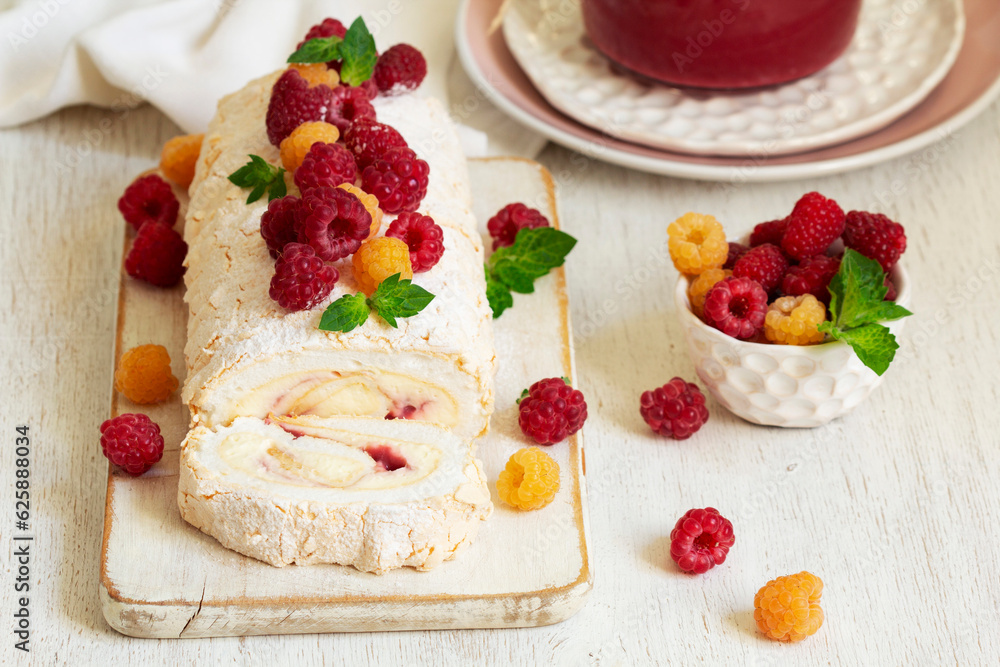Meringue roll with butter cream and raspberry curd, decorated with berries on a light background.
