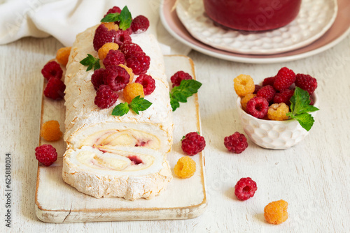 Obraz na płótnie Meringue roll with butter cream and raspberry curd, decorated with berries on a light background. w salonie