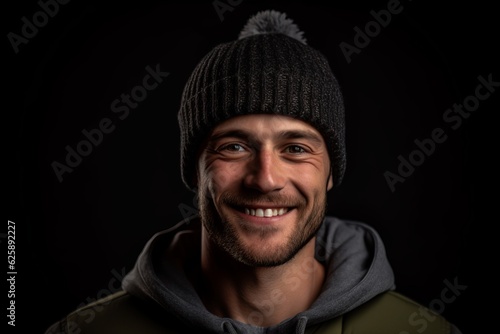 Portrait of a smiling young man in a hat and jacket on a black background photo