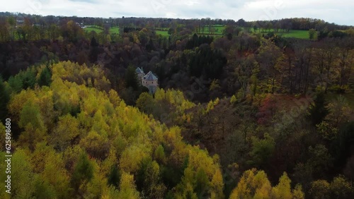 Castle tower hiding between trees of autumn forest, aerial drone view photo