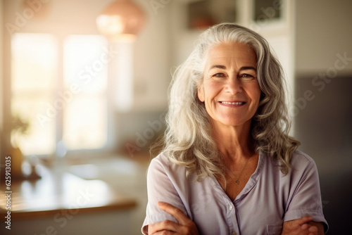 Portrait of a self confident and glamorous woman in her 60s with beautiful white natural hair at home, interior background