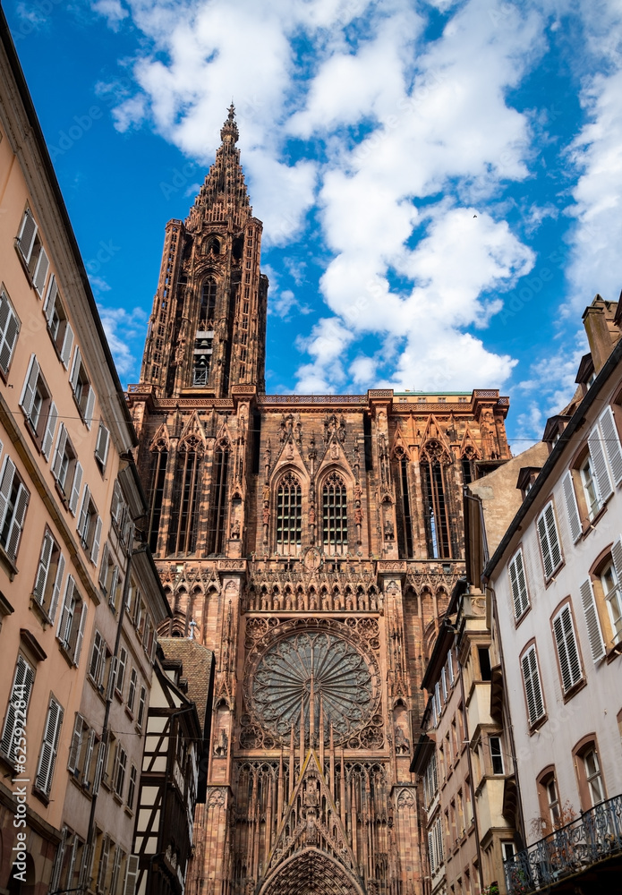 Fototapeta premium Bell tower and west front facade of Strasbourg Cathedral (Cathedral of Our Lady) in Alsace, France. Church built with reddish-brown sandstone with rose window and details. Major monument and sight