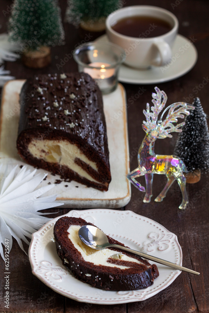 Chocolate roll stuffed with butter cream and pineapple on a Christmas background. Rustic style.